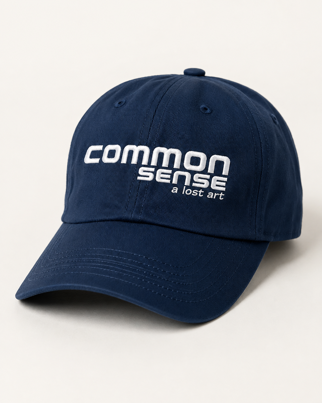 A navy blue baseball cap with white embroidered text reading 'common sense a lost art' on the front, photographed on a clean off-white background.