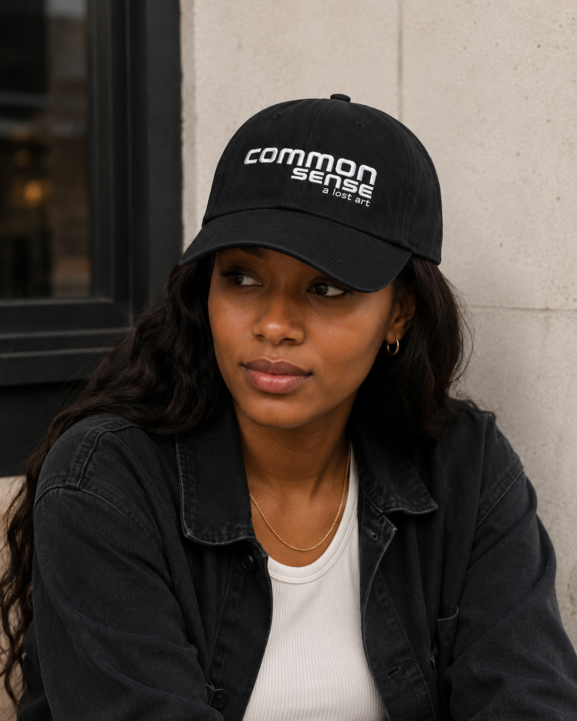 A woman wearing a black baseball cap with the white embroidered text 'common sense a great.
