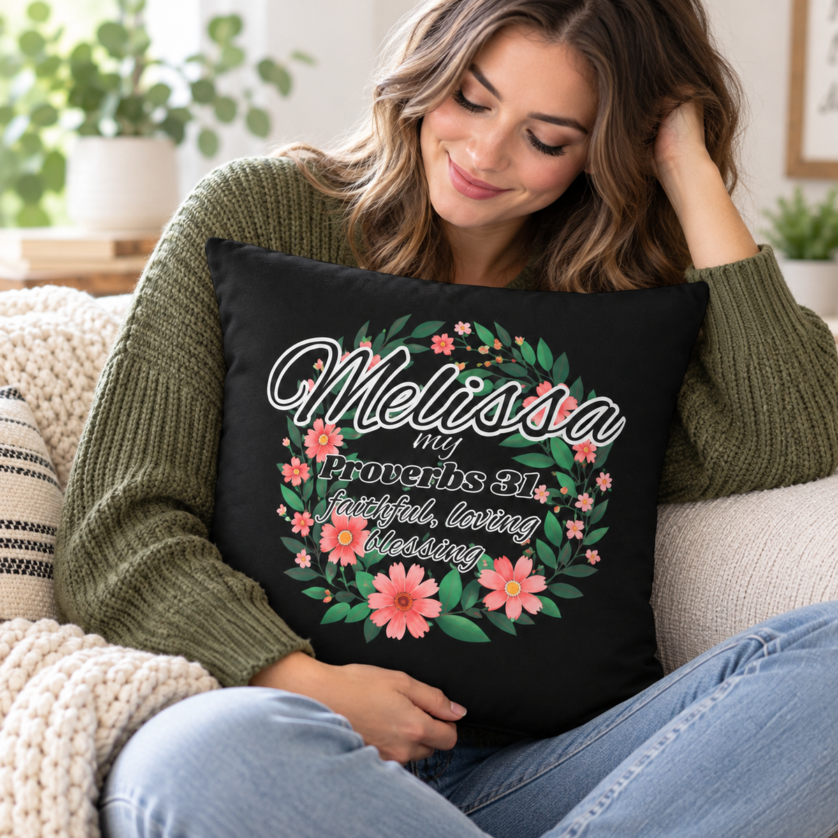 A woman sitting on a couch holding a black throw pillow with a personalized floral wreath design and the text 'Melissa my Proverbs 31:10 faithful, loving, blessing'.