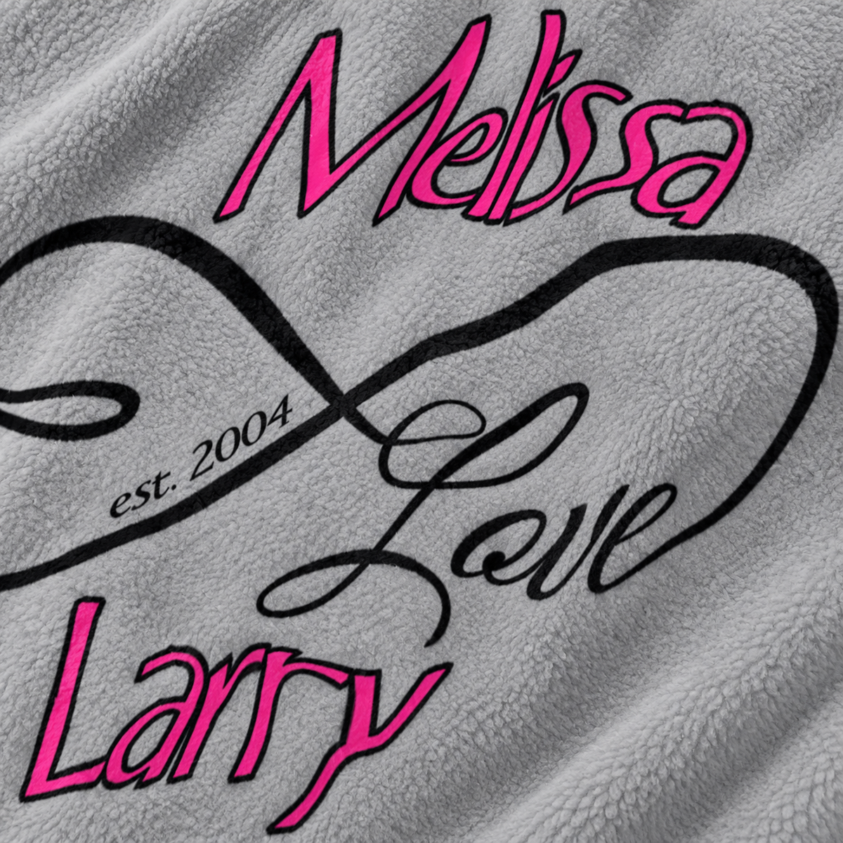 Close-up of a gray textured fleece blanket featuring custom printed text in pink and black. The design includes the names 'Melissa' and 'Larry' in pink script, a large black infinity symbol, the phrase 'est.