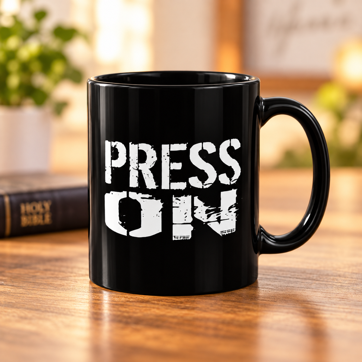 A black ceramic coffee mug with the words 'PRESS ON' printed in a distressed white typewriter font, sitting on a wooden table with a blurred background.