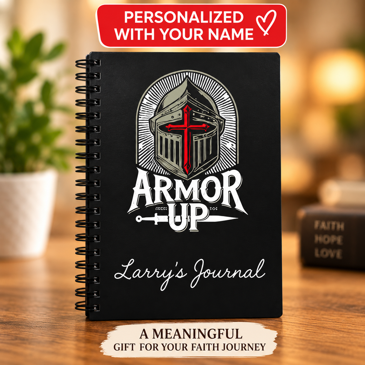 A black spiral-bound journal standing on a wooden surface, featuring a knight helmet with a red cross and the words 'ARMOR UP' and 'Larry's Journal' on the cover. A red banner at the top reads 'PERSONALIZED WITH YOUR NAME,' and a cream banner at the bottom says 'A MEANINGLEF GIFT FOR YOUR FAITH JOURNEY.