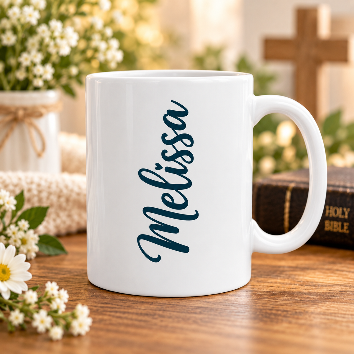 A white ceramic coffee mug with the name 'Melissa' printed vertically in dark teal script, set on a wooden table with flowers, a cross, and a holy bible in the background.