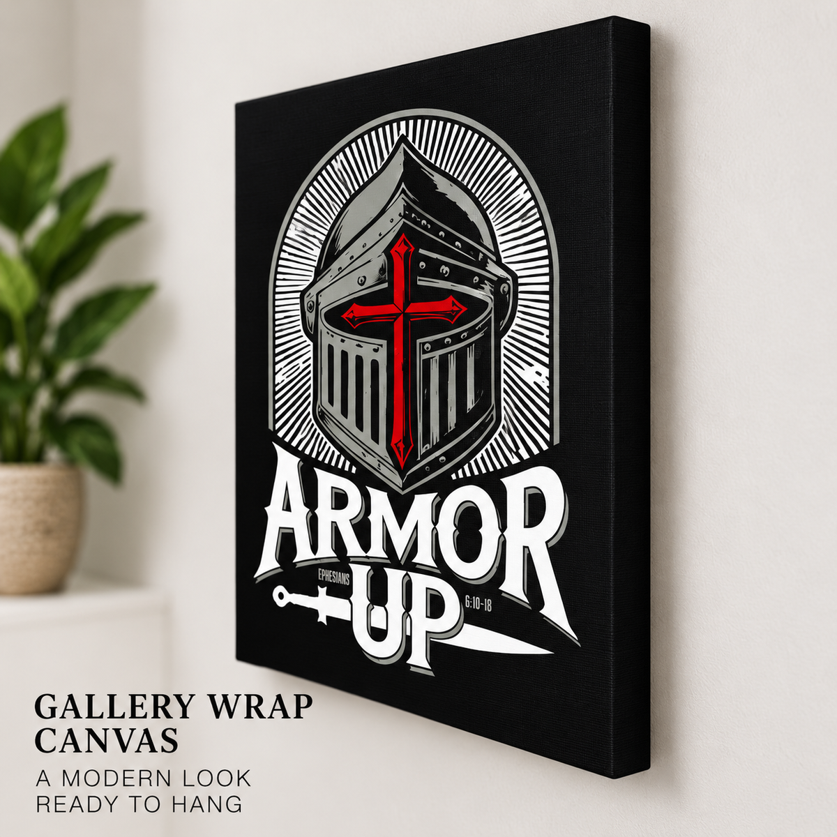A gallery-wrapped canvas print featuring a stylized knight helmet with a red cross on a black background and the words 'ARMOR UP' in white, shown hanging on a light wall with a plant nearby.