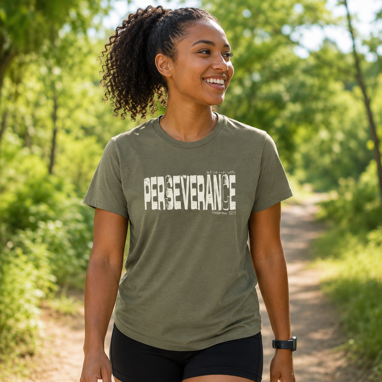 Black woman wearing a Military Green Perseverance Christian shirt while walking on a wooded trail