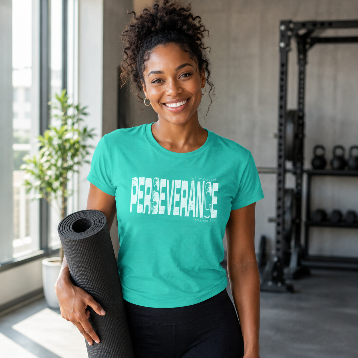 Black woman wearing a teal Perseverance Christian shirt while carrying a workout mat in a gym