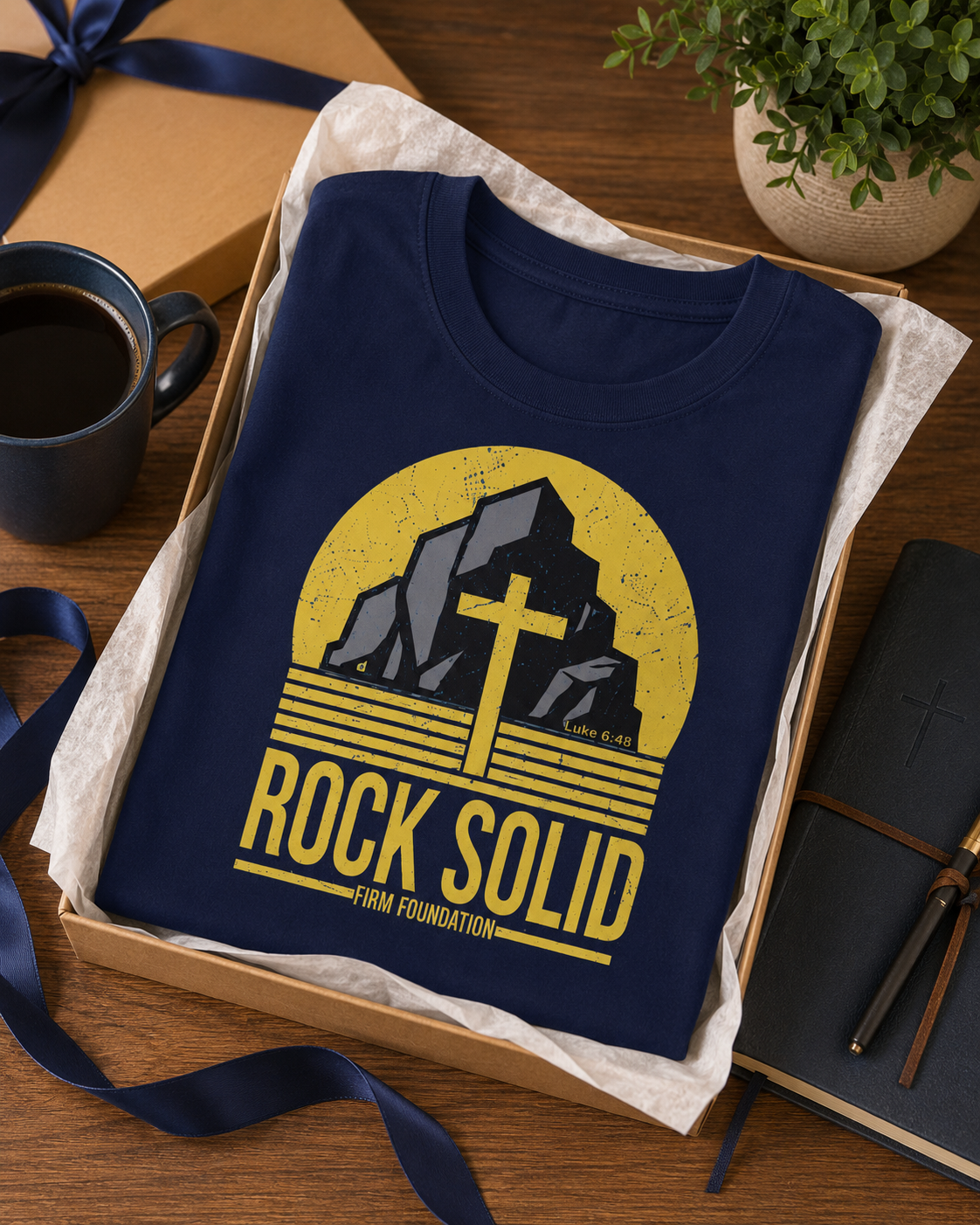 Navy Rock Solid Christian T-shirt arranged as a thoughtful Christian gift with a gift box, journal, and coffee