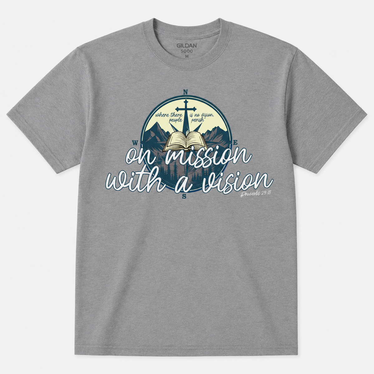 A heather gray crewneck t-shirt by Gildan featuring a circular graphic with a cross, open book, mountains, and compass directions, overlaid with the text 'on mission with a vision' in white script.